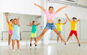 Young girls and boys jumping together in dance studio.