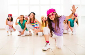 Group of little girls dancing. Focus is on foreground, on a little girl in a dance move looking at the camera.