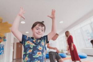 Small nursery school children with a female teacher on the floor indoors in the classroom, doing exercise. Jumping over hula hoop circles track on the floor. High quality photo